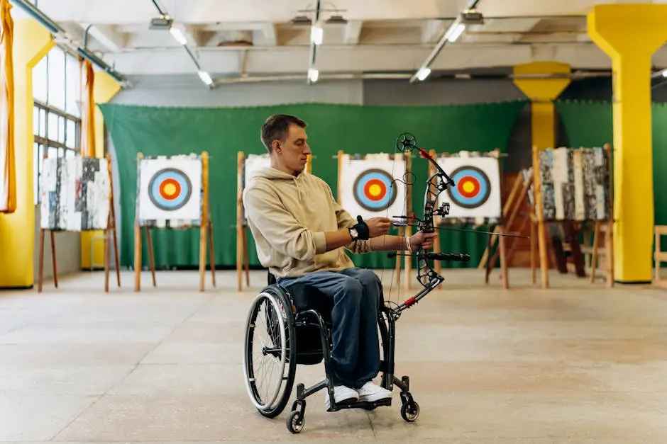 Man in a wheelchair practicing archery indoors, demonstrating skill and determination.