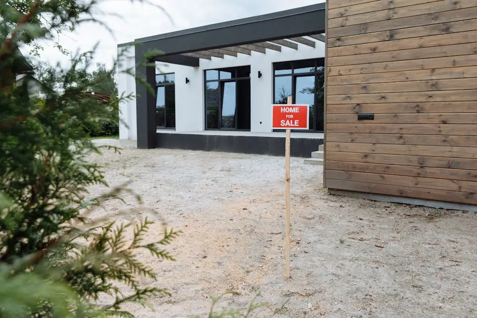 Modern house exterior with a ‘Home for Sale’ sign in front yard.