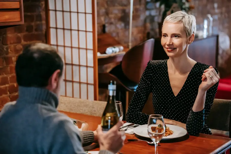 A couple enjoying a romantic dinner in a cozy restaurant setting, sharing wine and pasta.