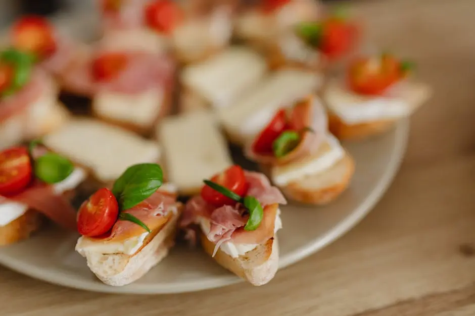 Delicious bruschetta appetizers with prosciutto, cheese, and cherry tomatoes on a serving platter.