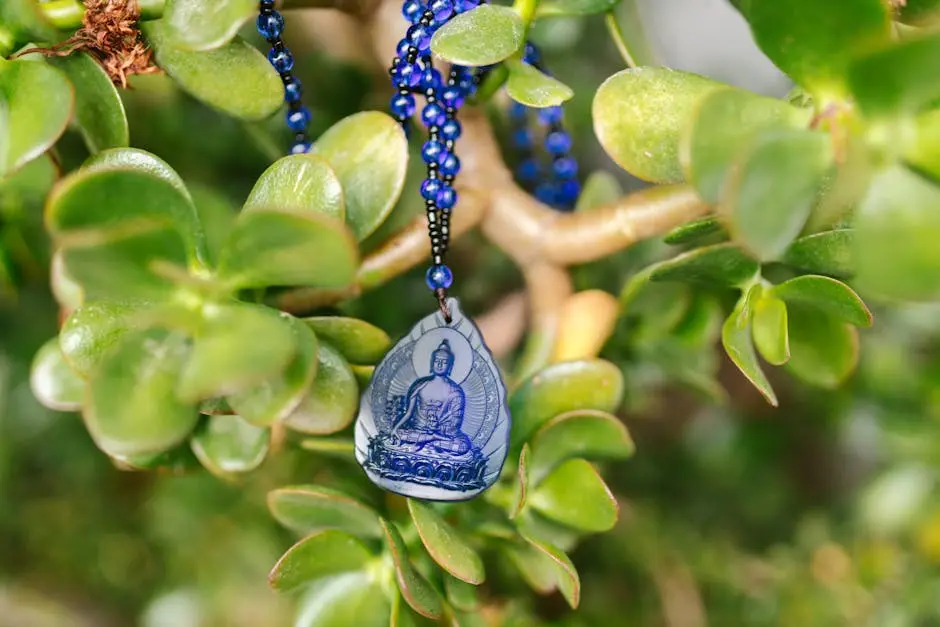 Close-up of a blue Buddha pendant hanging on a jade plant symbolizing spirituality and peace.