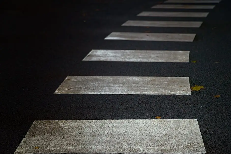 Detailed view of a pedestrian crosswalk on a textured asphalt road, ideal for urban themes.