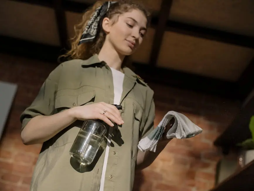 A young woman with curly hair cleans a home interior with a spray bottle and cloth.