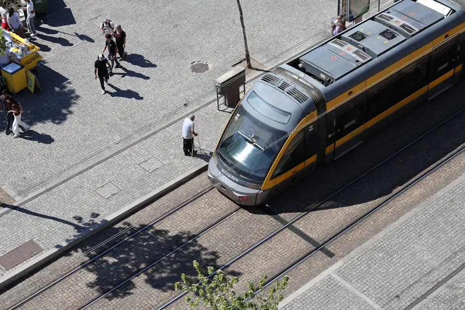 A bird&rsquo;s-eye view of a modern tram on tracks in Porto, Portugal with people walking nearby.