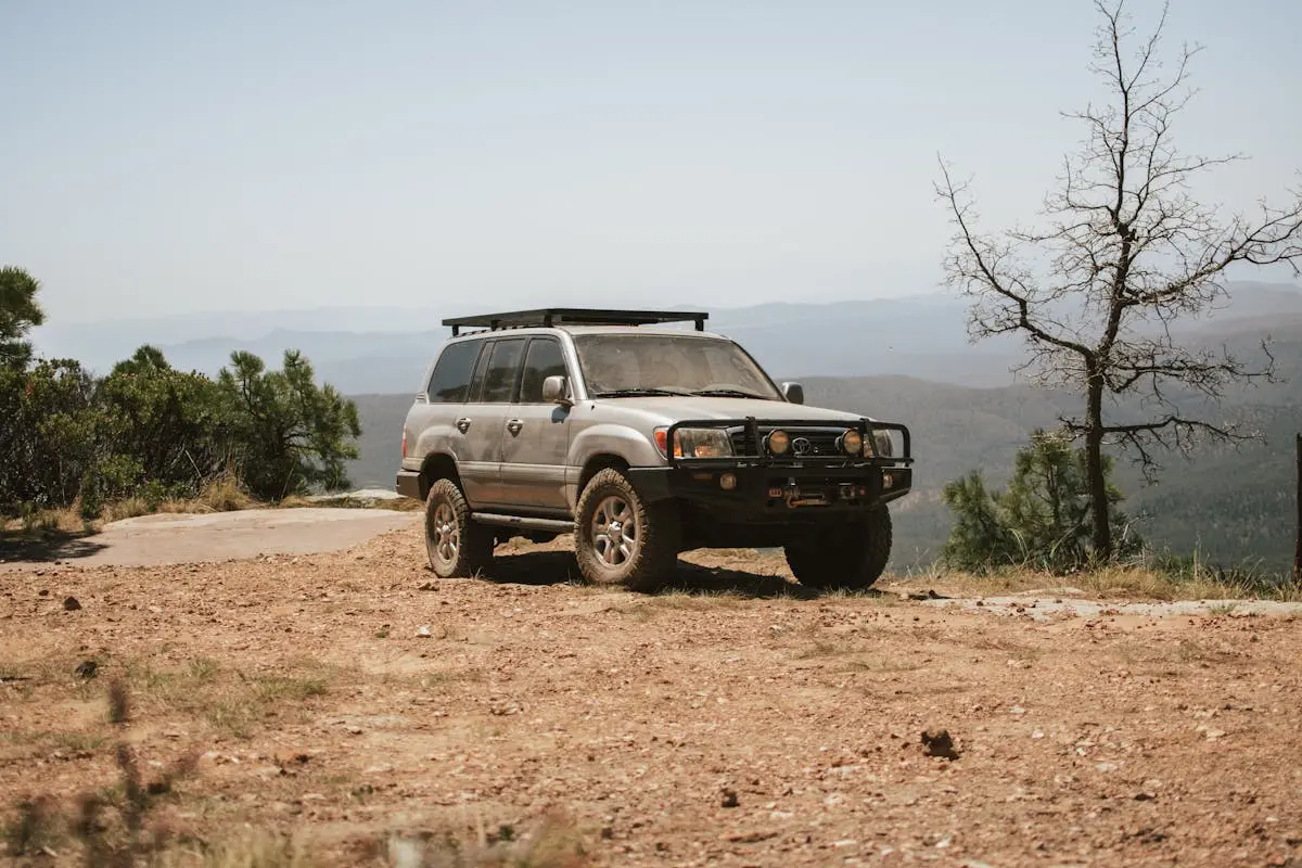 Sturdy off-road SUV parked on a dirt trail in Arizona with scenic mountain background.