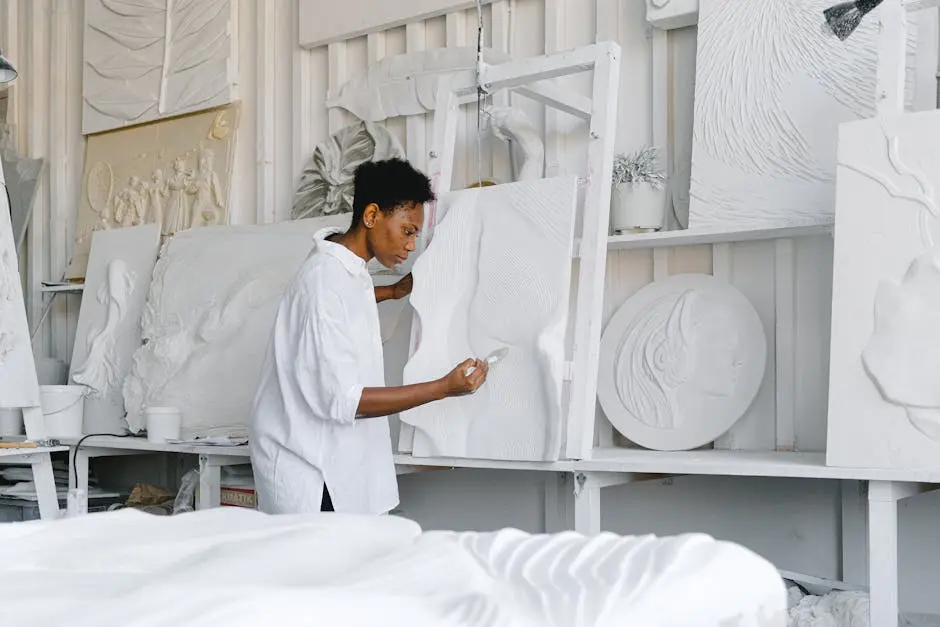 A talented artist focuses on sculpting a textured artwork in a bright studio space.