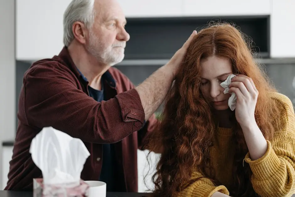 A father consoles his distressed daughter indoors, showcasing love and support.
