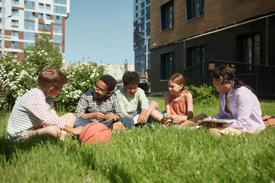 A diverse group of kids sitting on grass, having fun together under a clear blue sky.