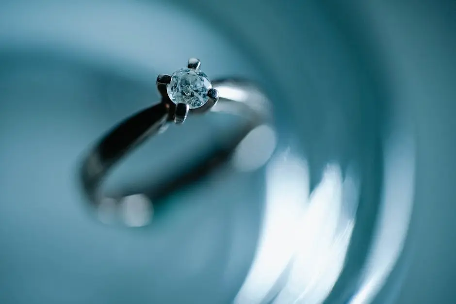 Close-up of a diamond engagement ring on a shimmering blue surface, evoking elegance and romance.