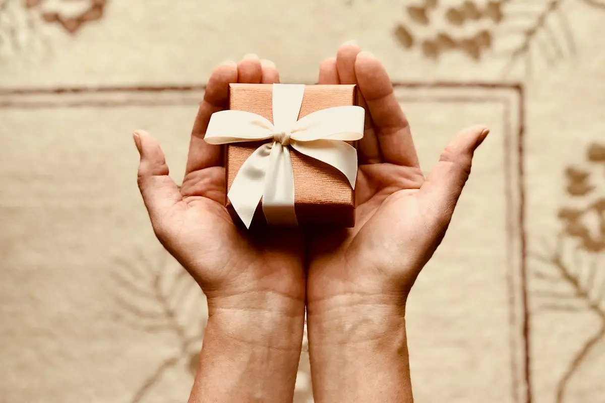Close-up of hands holding a beautifully wrapped gift box with a ribbon, perfect for celebrations and surprises.