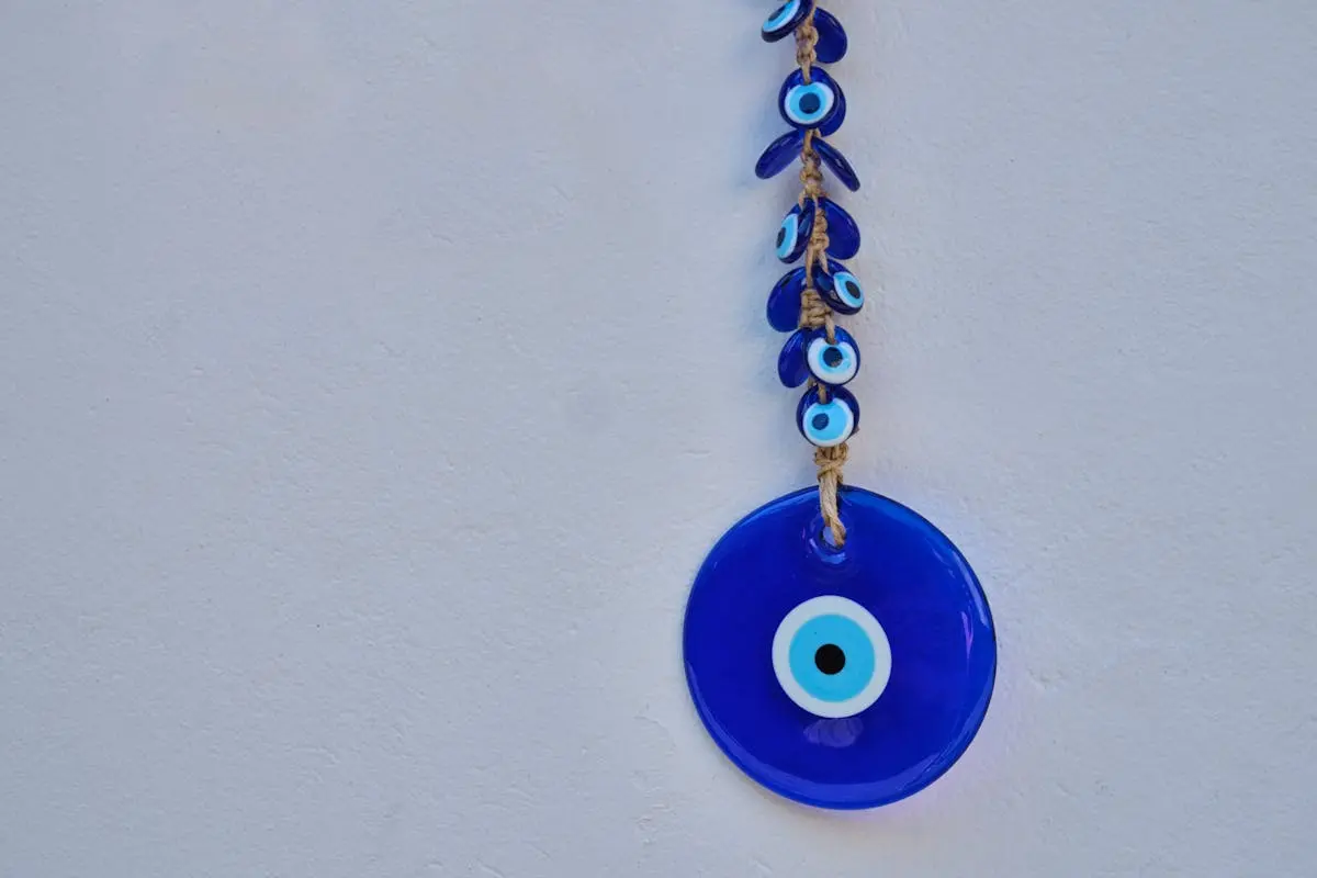 Hanging blue evil eye charm for protection and good luck on a white background.