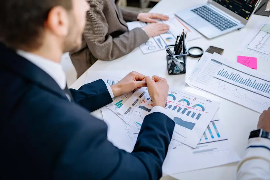 Business team analyzing financial graphs at a meeting table, fostering collaboration in an office environment.