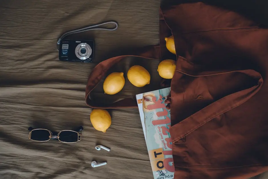 Aerial view of a tote bag with lemons, a magazine, and summer accessories on display.