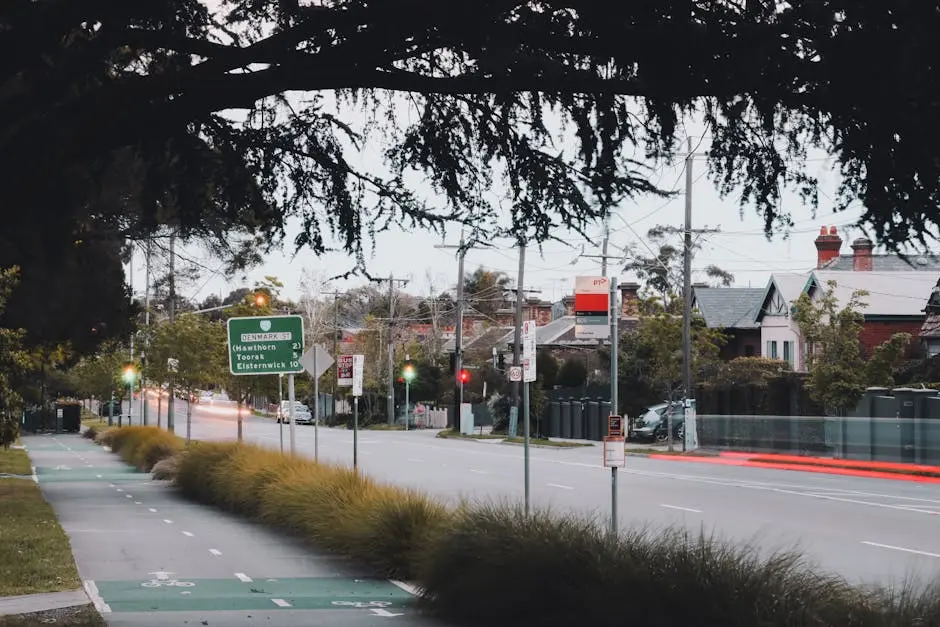 A tranquil residential street scene with a bike lane and traffic lights in the evening.