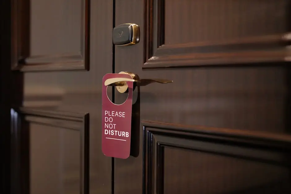 A wooden hotel door with a ‘Please Do Not Disturb’ sign hanging on the handle.