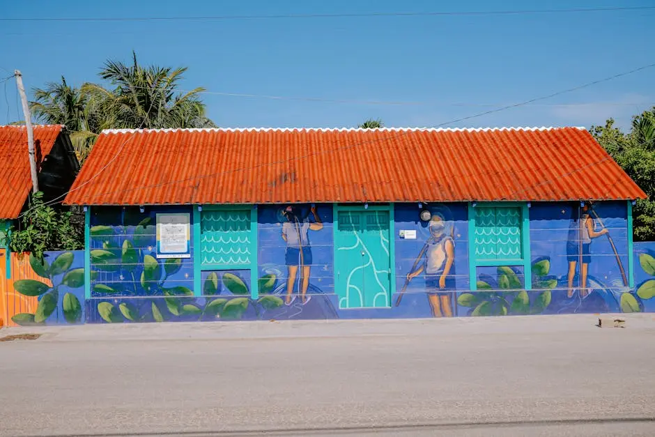 Brightly painted house with mural and red roof under clear sky.