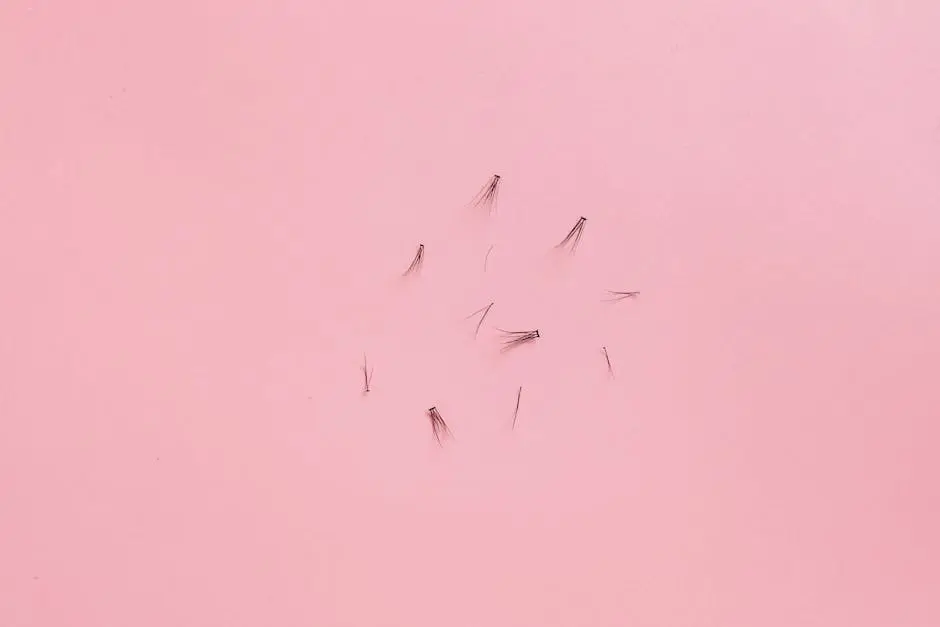 Top view of scattered false eyelashes on a pink background, perfect for beauty and fashion concepts.