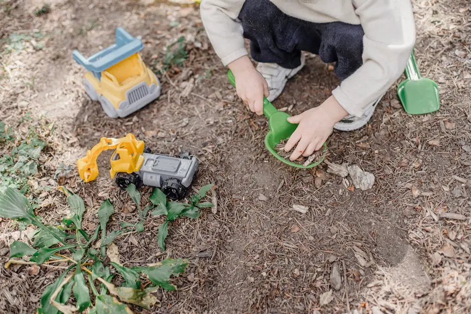 A young child enjoys playing with toy trucks in a garden, symbolizing fun and creativity.