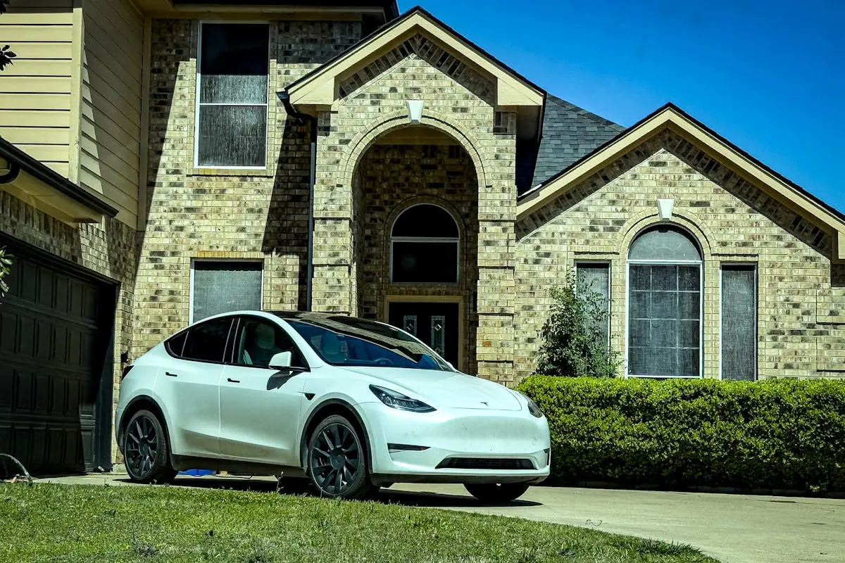 Stylish white electric car parked by a classic brick house in sunny Mansfield, Texas.