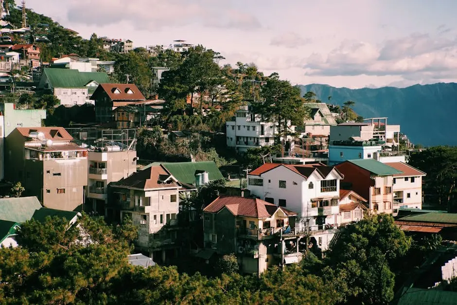 Aerial view of a scenic mountain town with modern houses and lush greenery under a clear sky.
