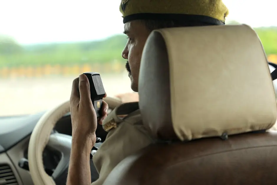 A police officer communicates via radio in a patrol car, maintaining public safety.