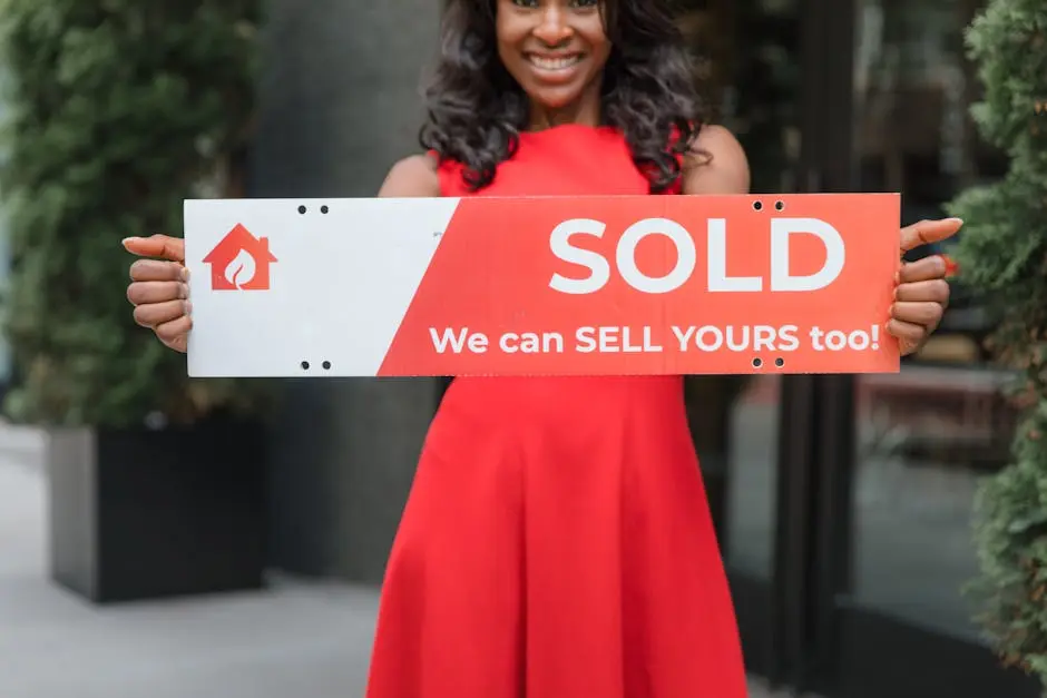 Smiling woman holding a &lsquo;Sold&rsquo; sign, symbolizing successful real estate sales.