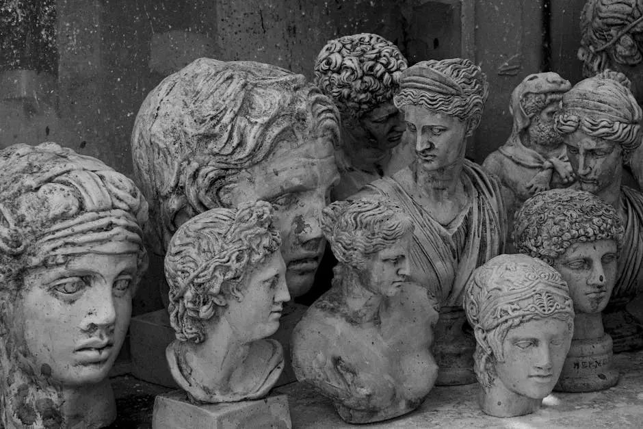 A group of vintage stone head bust sculptures in grayscale, depicting ancient figures.