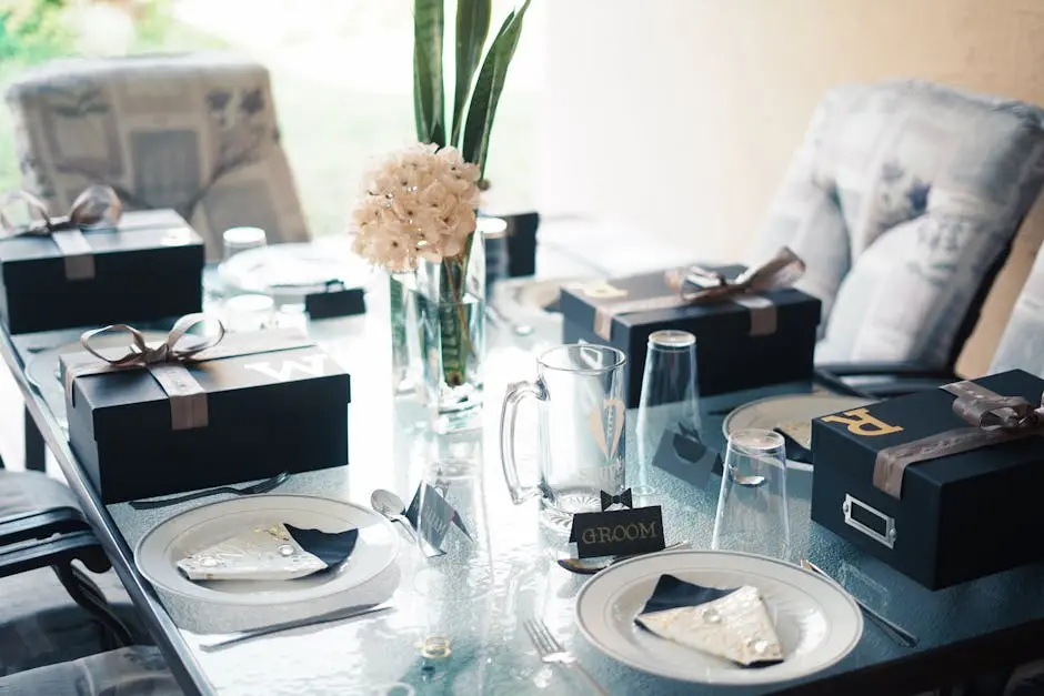 Chic wedding reception table with elegant gift boxes, floral decorations, and fine dining setting.