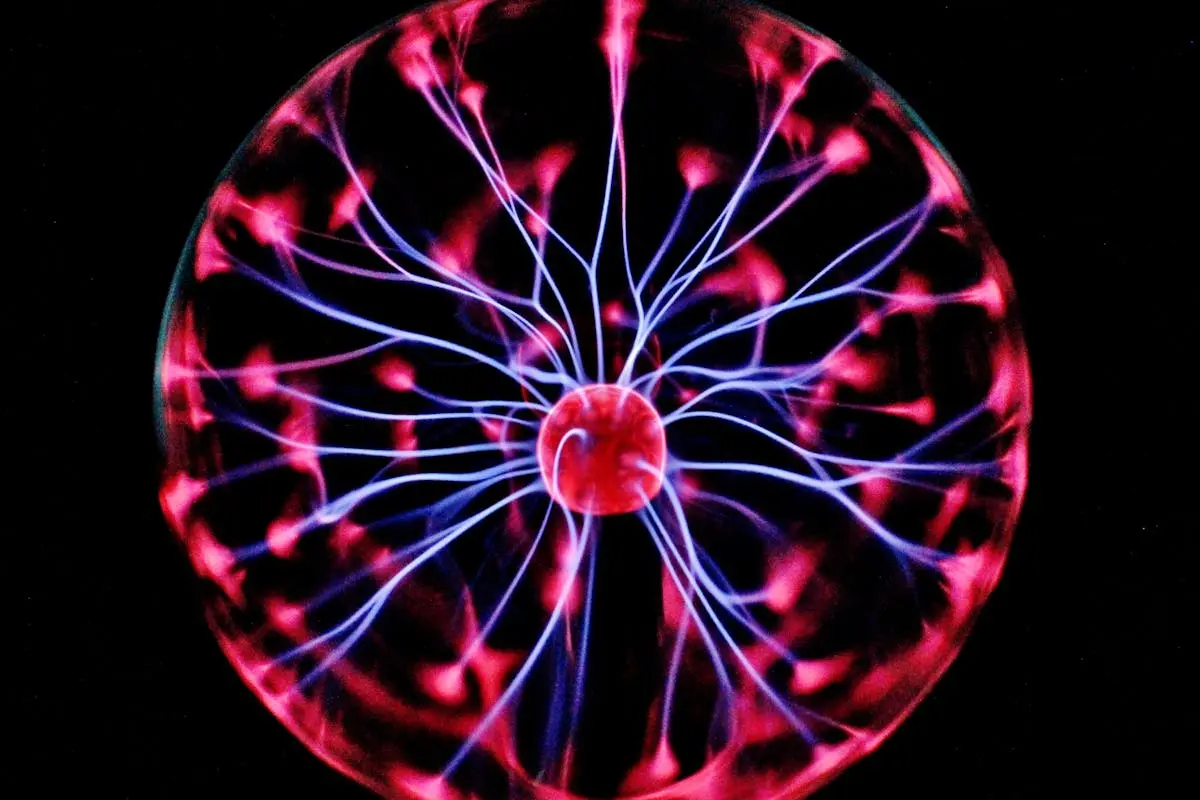 Close-up of a plasma globe with vibrant neon sparks against a dark background.