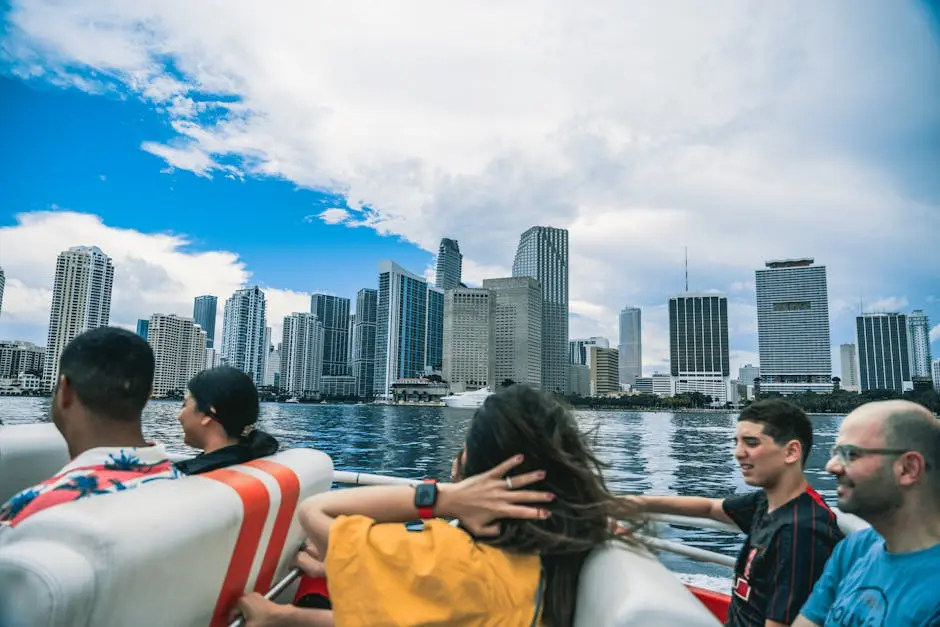 Group enjoying a boat ride with stunning view of city skyline under a bright sky.