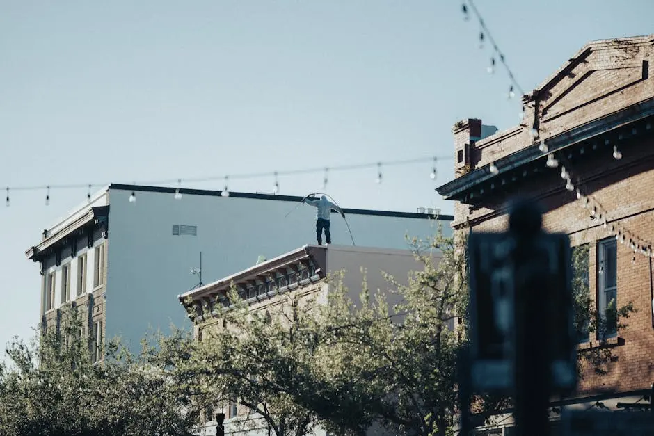 A person working on a rooftop in an urban setting with historic architecture and string lights.