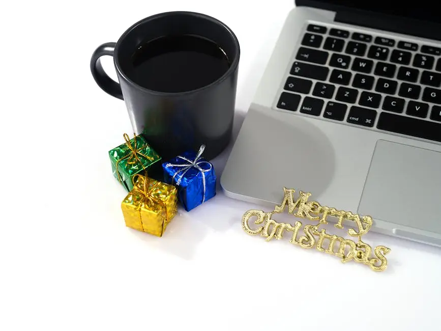A festive desk setup featuring a coffee cup, small gifts, and a laptop with ‘Merry Christmas’ text.
