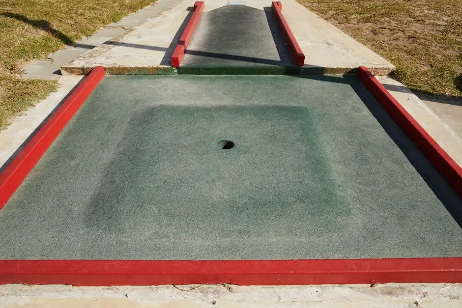 Small round hole in center of square dark green area for mini golf in daytime