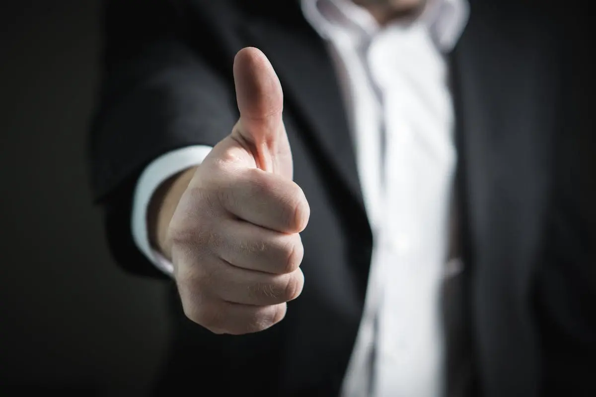 A close-up of a man’s thumbs up gesture, symbolizing success and agreement.