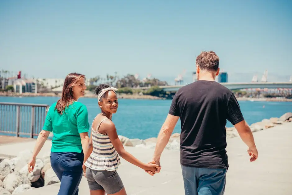 Joyful family enjoying a sunny day near the water, holding hands in unity.