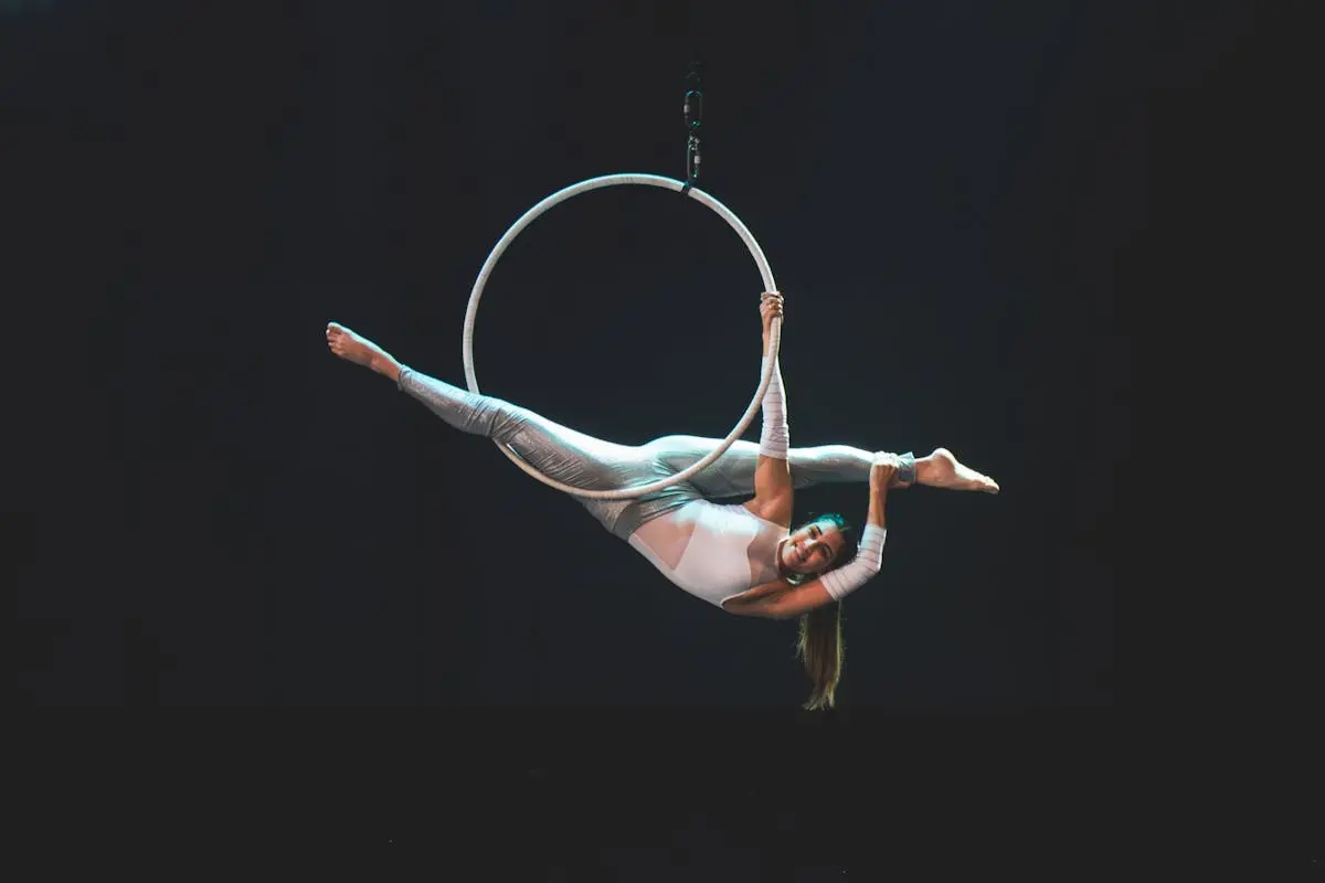 Aerial view of a female acrobat gracefully performing on a hoop with artistic flair.