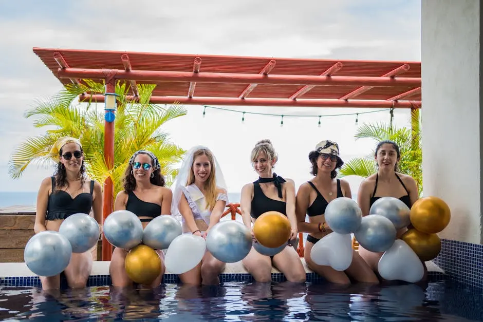 Group of women celebrating a bachelorette party outdoors with balloons by the pool.
