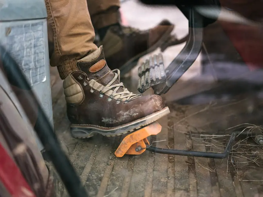 A rugged work boot presses a pedal in a dusty vehicle cabin, showcasing labor and transport themes.