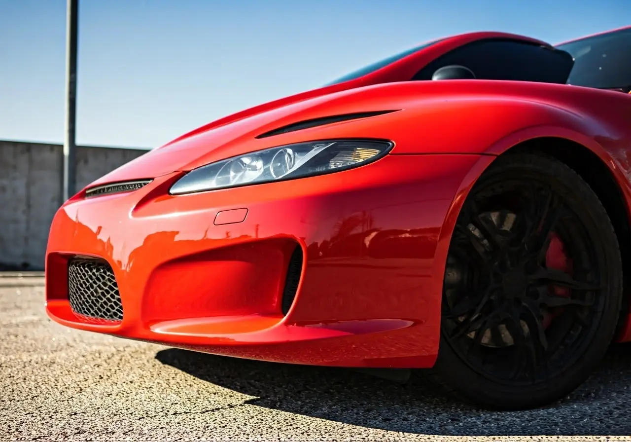 A shiny red car reflecting sunlight, showcasing ceramic coating. 35mm stock photo
