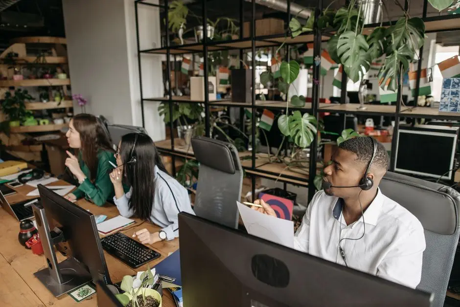 A diverse team collaborates in a modern office with plants and technology.