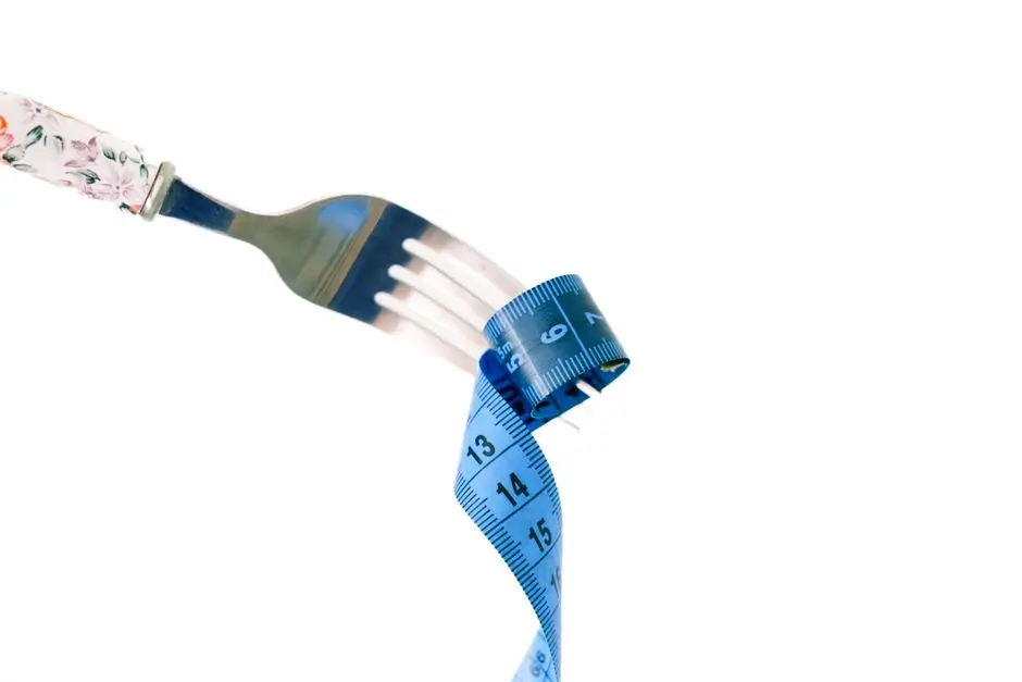A fork twirls a blue measuring tape, symbolizing weight management and health.