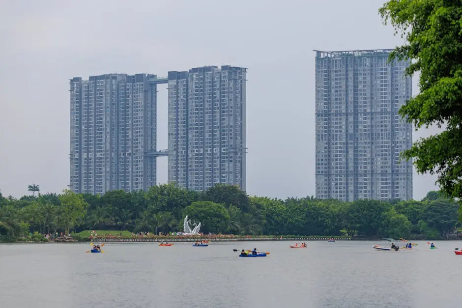 A cityscape featuring tall skyscrapers by a river with people kayaking on the calm water.