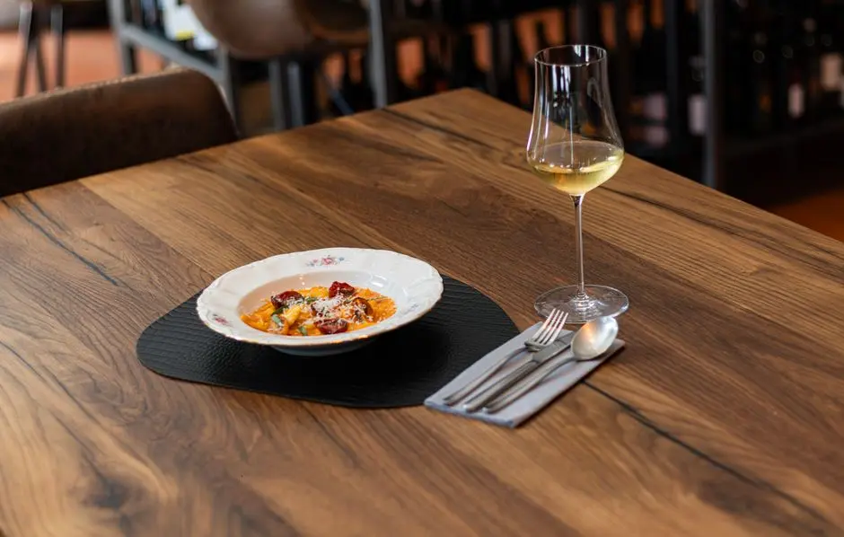 Elegant presentation of Italian dish with wine on wooden table in a cozy setting.