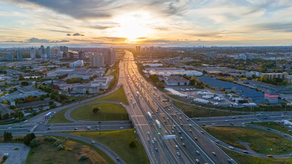 Dramatic aerial view of a busy highway in Toronto at sunset with cityscape background.