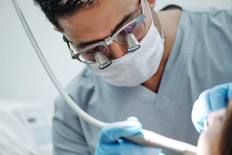 Dentist wearing magnifying glasses performing a dental procedure in a clinic.