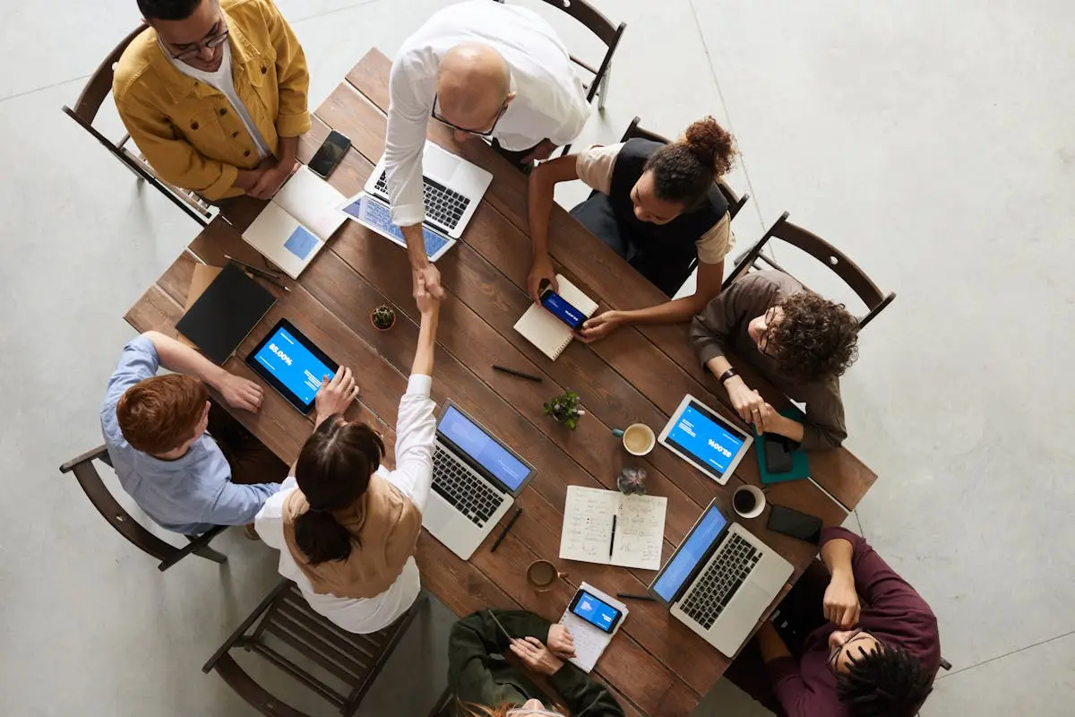 Top view of a diverse team collaborating in an office setting with laptops and tablets, promoting cooperation, team leadership.