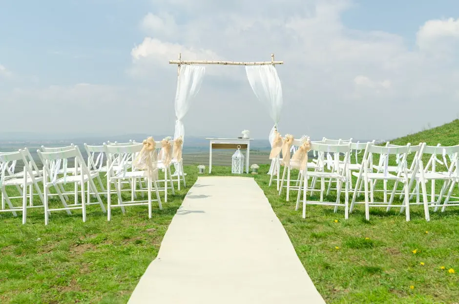 Elegant outdoor wedding setup with chairs and arch under a blue sky.