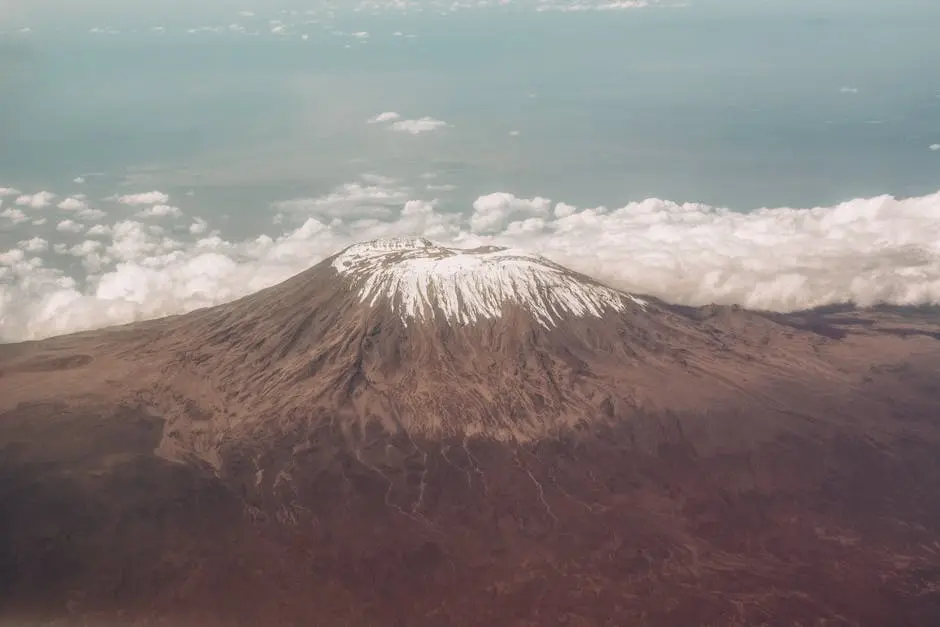 Breathtaking aerial view of Mount Kilimanjaro’s snow-capped peak surrounded by clouds.