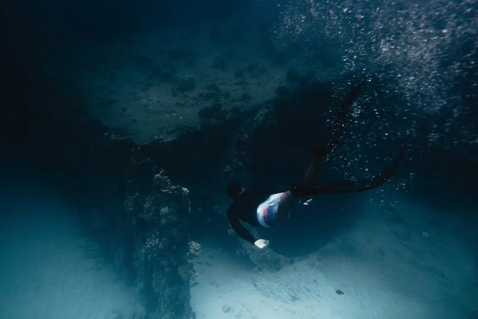 A diver swims gracefully through a vibrant coral reef underwater, captured in motion.
