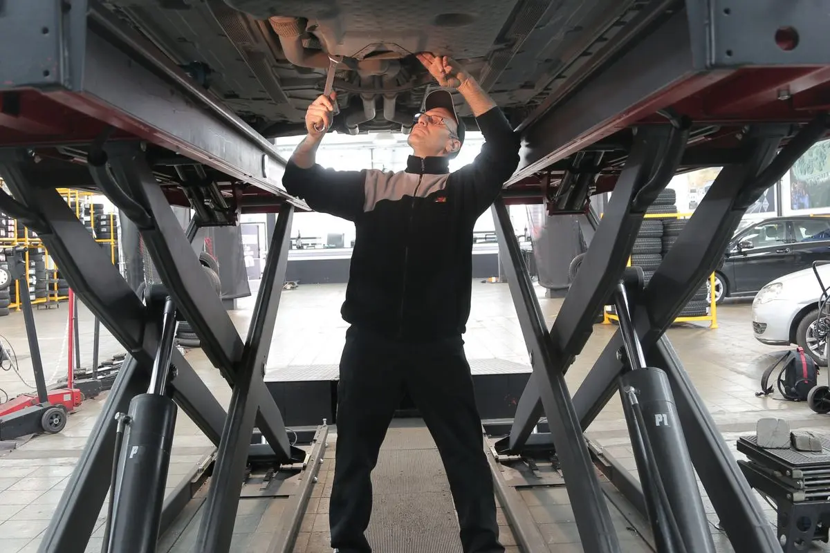 Mechanic inspecting and repairing a vehicle in a professional auto garage.